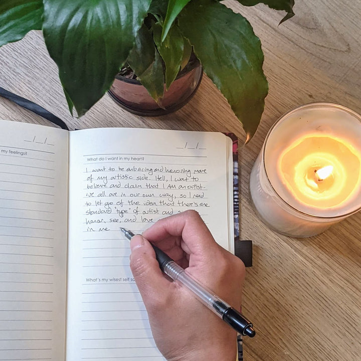 self care journaling in custom wellness journal by zenit with lit candle and green plant