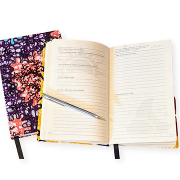 empower journal by zenit for self care journaling, one closed journal with pink, purple, and blue print pattern, one open with prompts for making progress towards goals and reflecting on progress and strengths